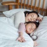 photo of woman and girl lying on bed