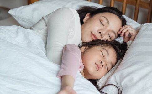 photo of woman and girl lying on bed