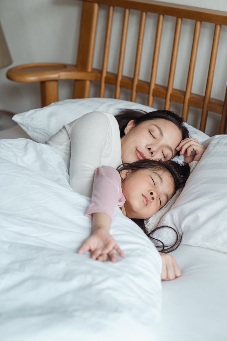 photo of woman and girl lying on bed